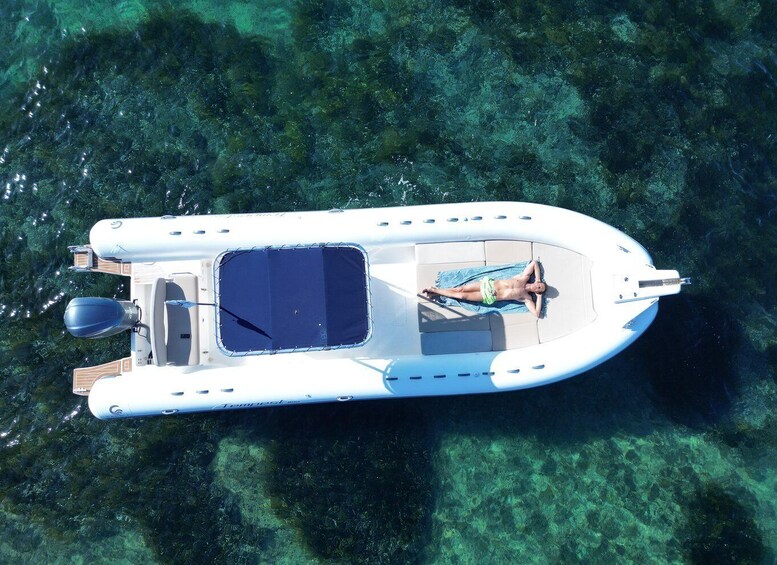 A small inflatable boat with a person lying on a mat, surrounded by clear water. 4