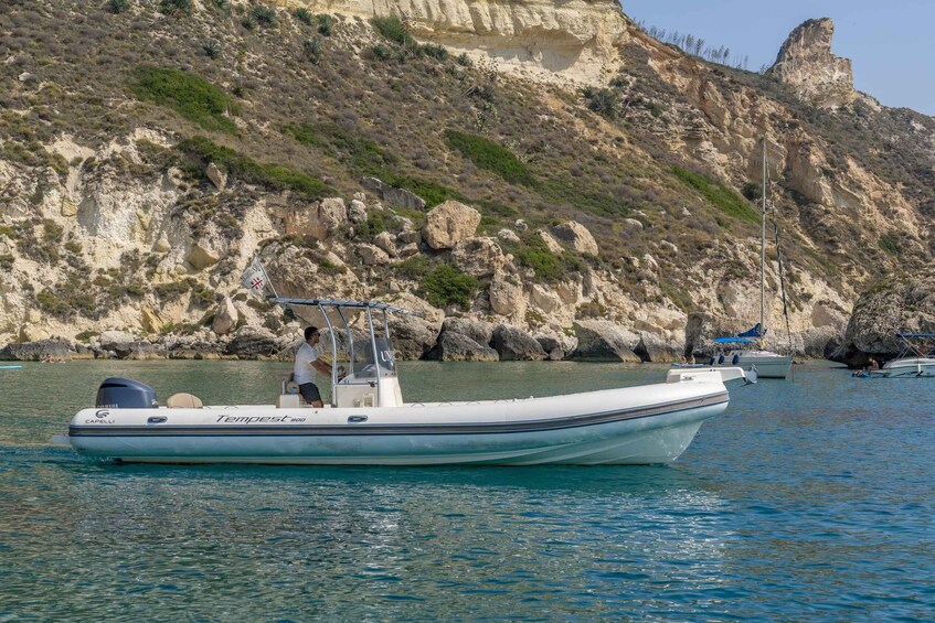 A boat named "Tempest 800" on calm water with rocky cliffs in the background. 3