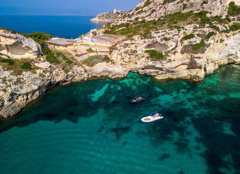 A coastal landscape with rocky cliffs, clear turquoise waters, and a boat anchored near the shore. 5