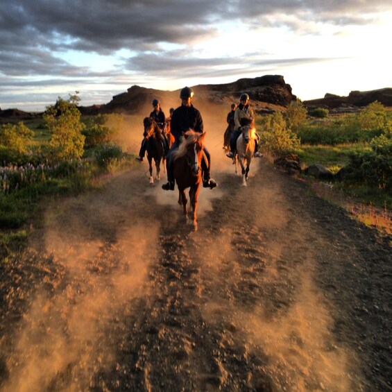 A group of people riding horses on a dirt road. 5