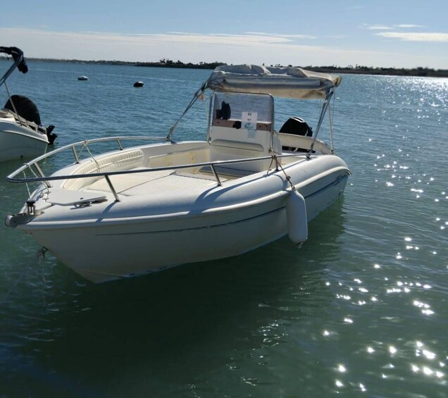 A white motorboat docked at a marina with calm water and a clear sky. 3