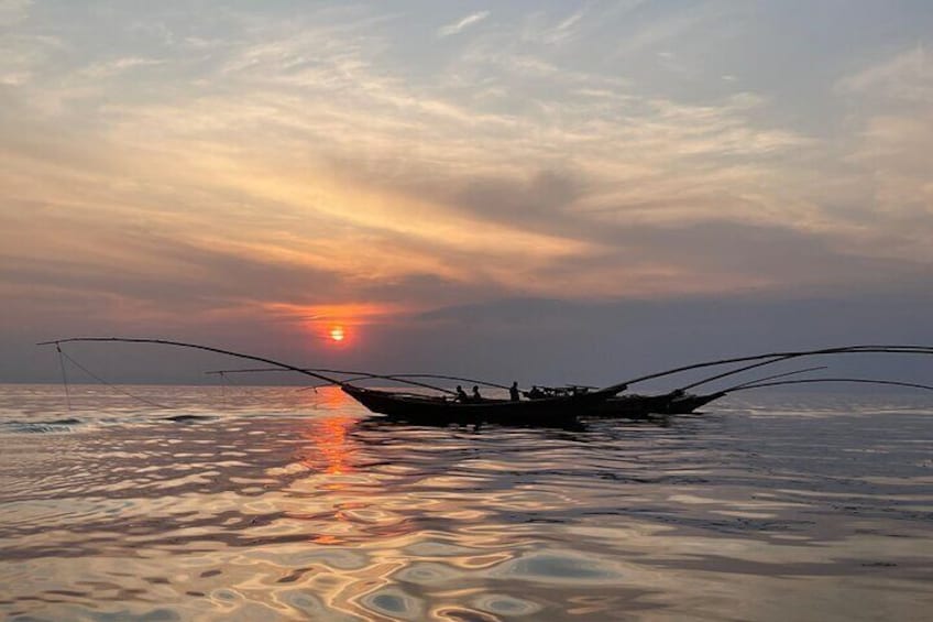 Un bateau traditionnel aux voiles déployées, naviguant sur une eau calme au coucher du soleil. 1