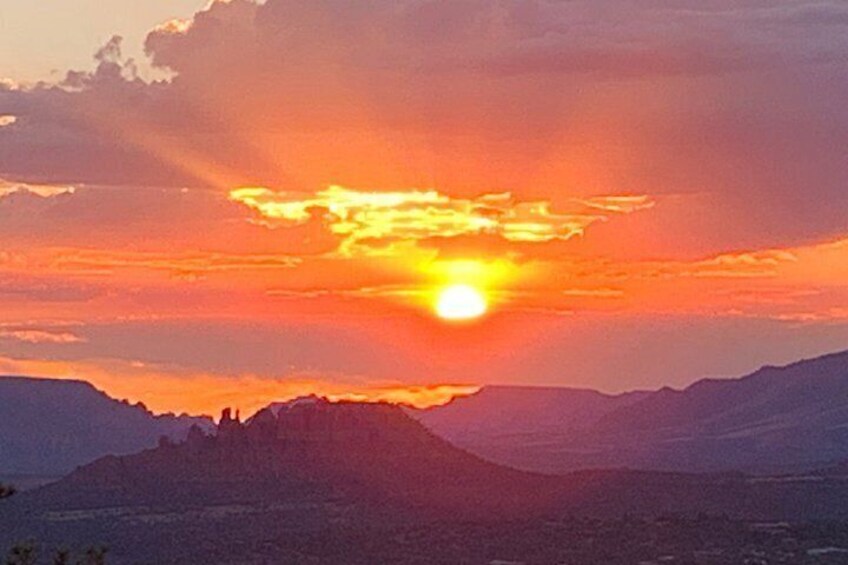 Solnedgang over et bjerglandskab med byens silhuet forgrunden. 3