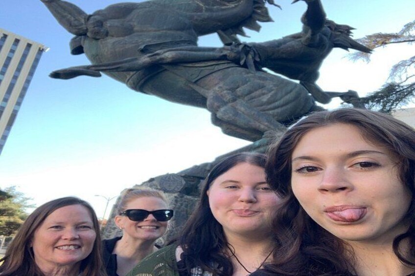 A group of people in front of a large bronze statue. 2