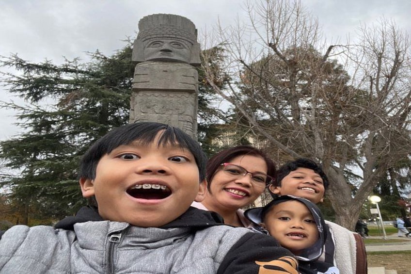 Una familia tomándose un selfie con un gran monumento de piedra al fondo. 3