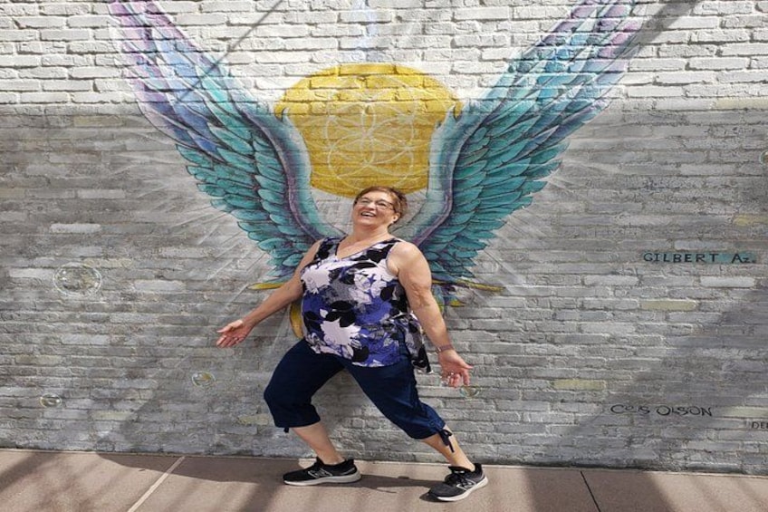Una persona in piedi di fronte a un muro con un murale di un angelo. 1