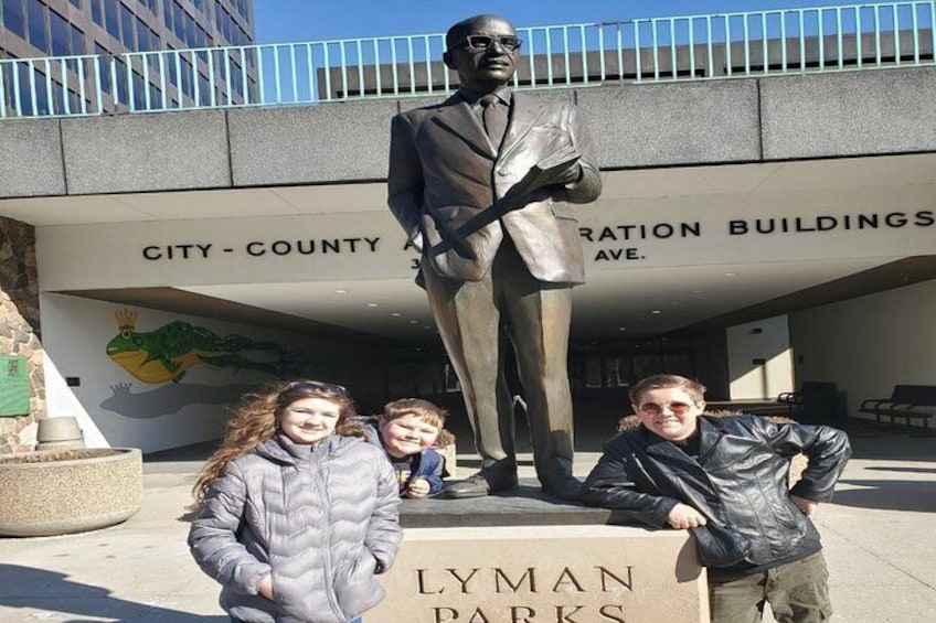 A statue of a man, a building with 'LYMAN PARKS' signage, and a bridge with railings. 4
