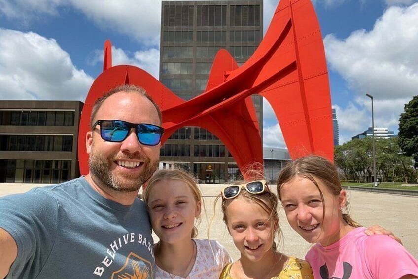 A family of four posing in front of a red sculpture. 3