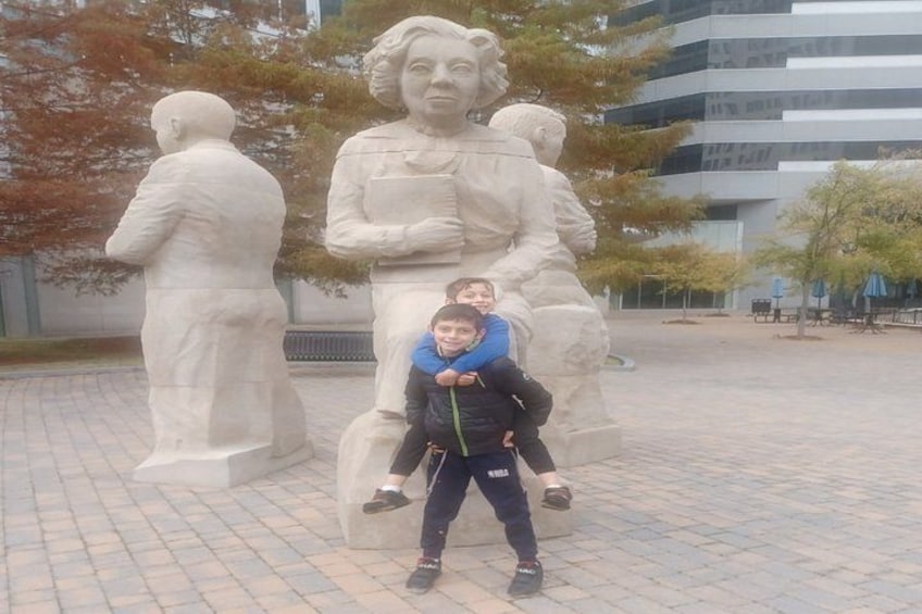 A statue of a person holding a book, with a child standing in front of it. 3