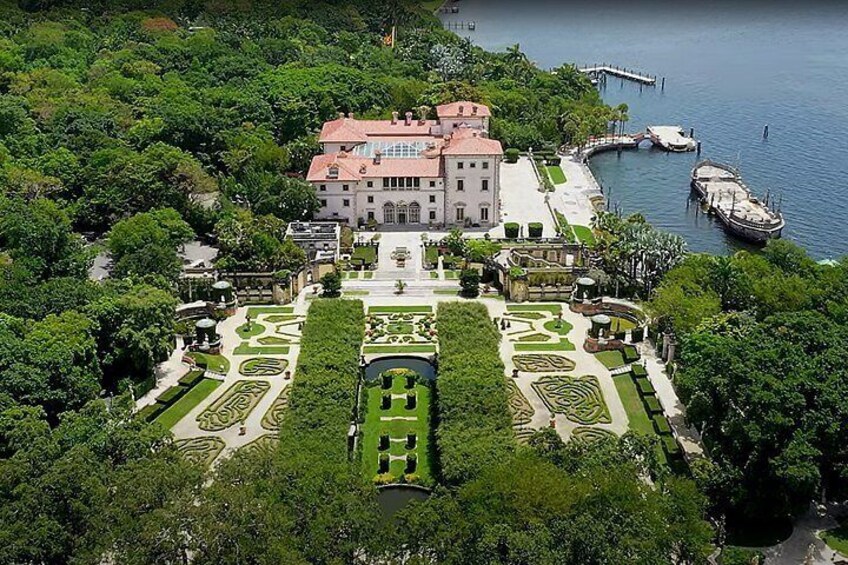A large, historic building with a formal garden and a waterfront. 2