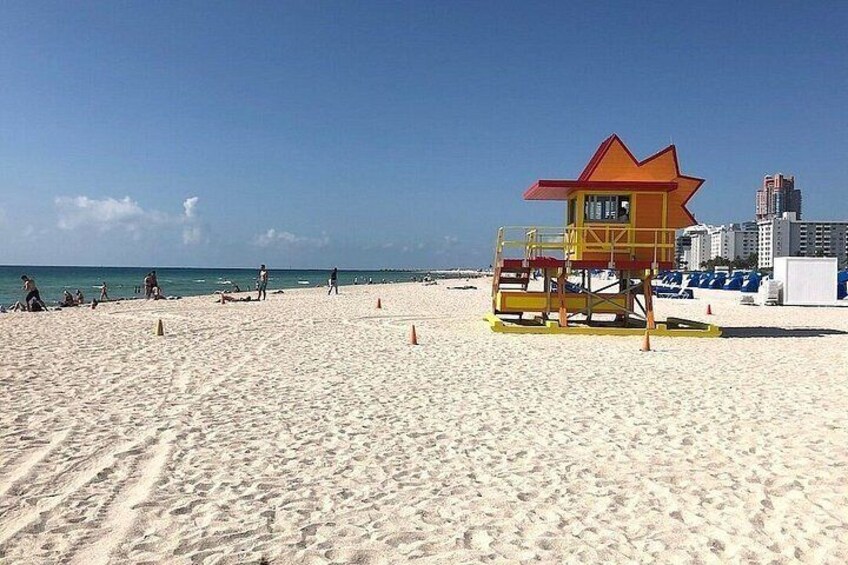 A beach with a lifeguard tower, sand, and a clear sky. 5