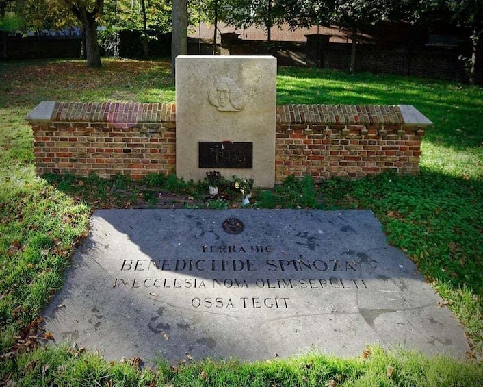 A memorial plaque with inscriptions, a brick wall, and a grassy area. 4