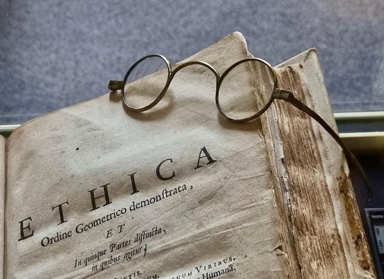An open book titled 'ETHICA' with glasses resting on top. 2