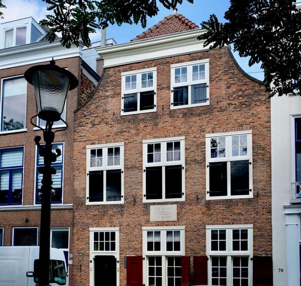 A brick building with multiple windows, a street lamp, and a sign. 3