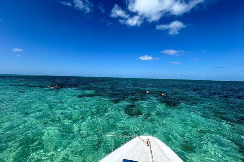 Un bateau sur une eau turquoise et limpide, avec une personne qui nage au loin. 1