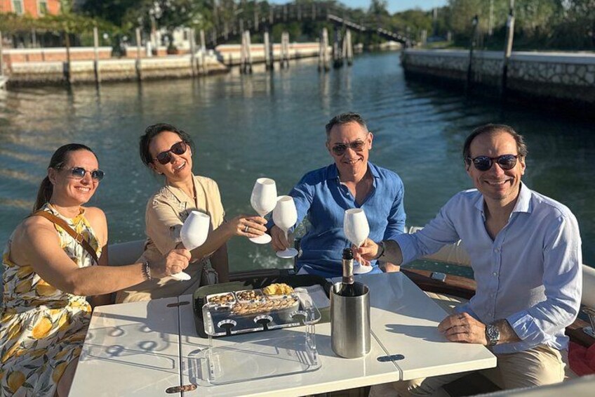 Cuatro personas brindando con copas de vino en un barco, con un río y un puente al fondo. 2