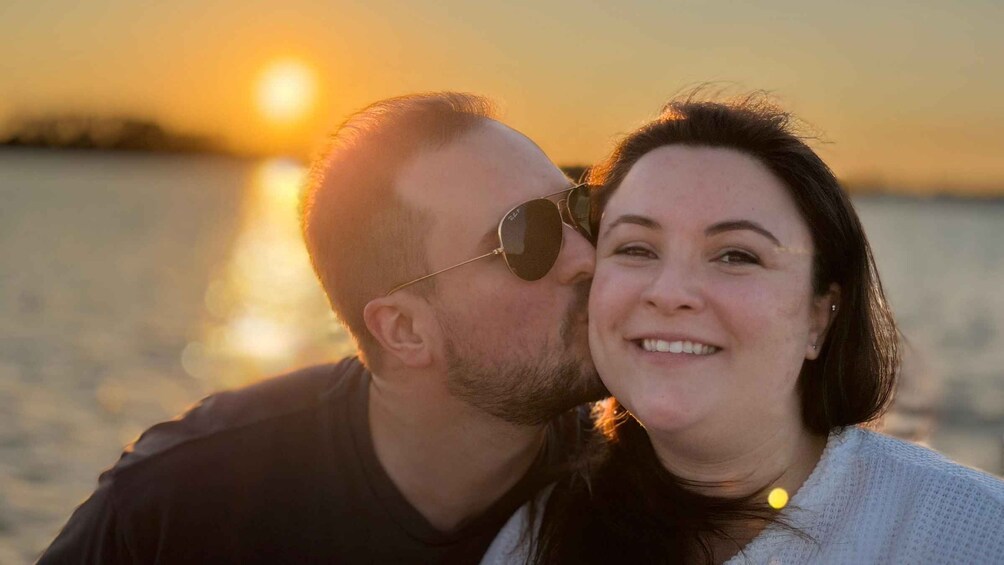 A couple embracing at sunset by the water. 1