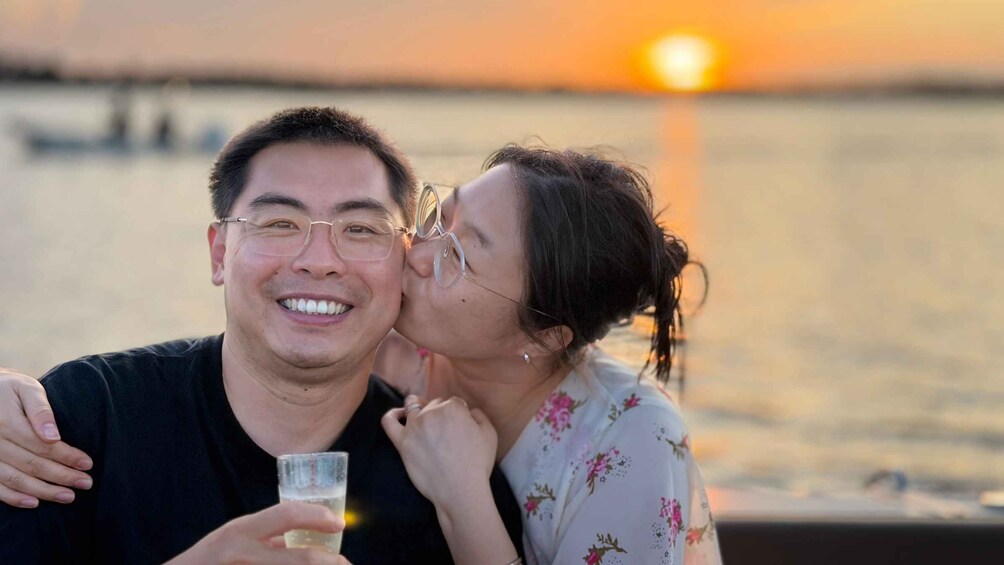 A couple sitting by a body of water during sunset. 5