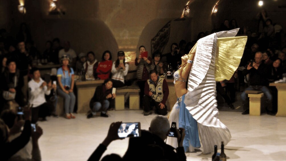 A person in a flowing dress being photographed by an audience. 2