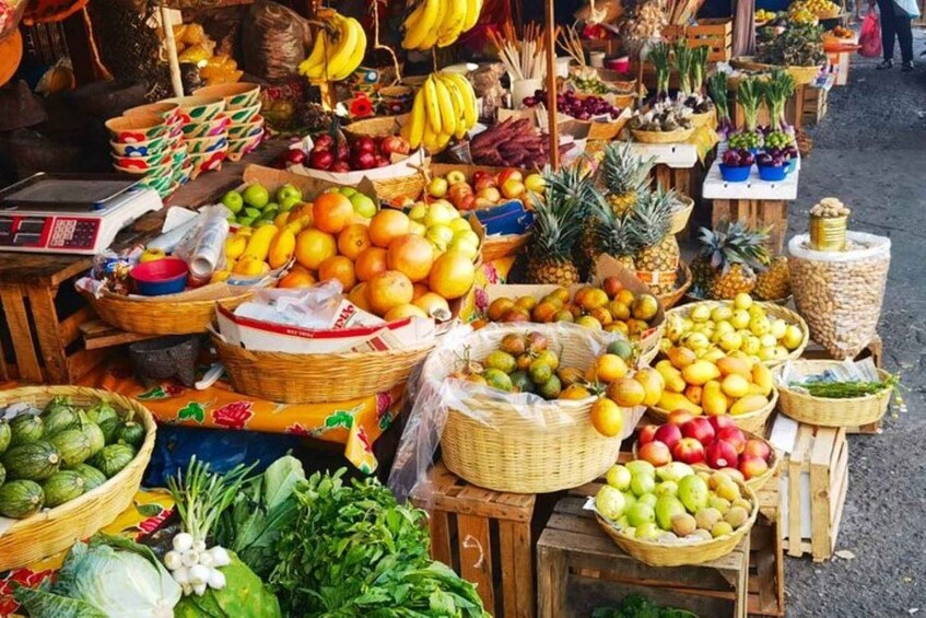 A vibrant outdoor market with various fruits and vegetables displayed in baskets and crates. 3