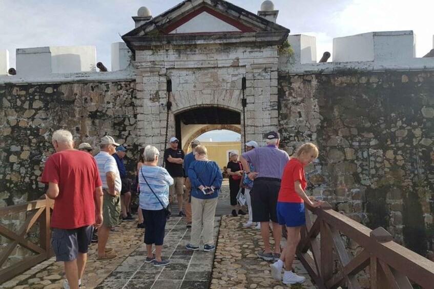 A group of people standing on a stone bridge with a stone archway in the background. 1
