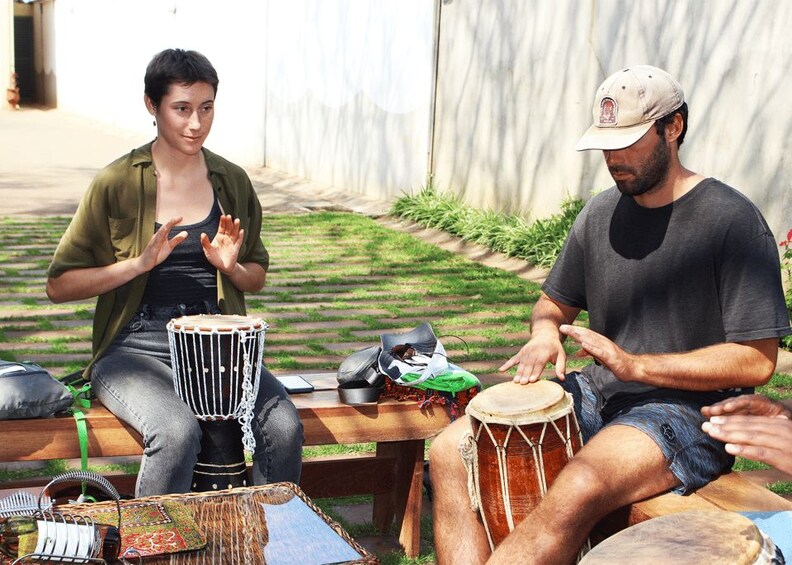 Two people playing drums outdoors. 4