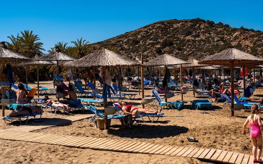 A beach with sun loungers and thatched umbrellas. 2