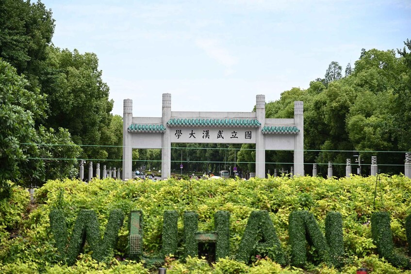 A traditional Chinese gate with green tiles and Chinese characters, surrounded by lush greenery. 4