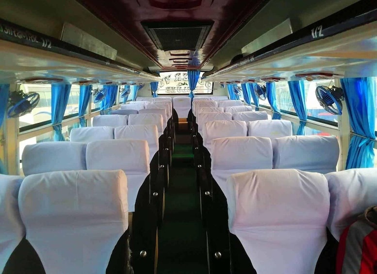 A train interior with rows of white seats and blue curtains. 2