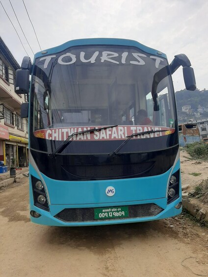 A turquoise bus with 'TOURIST' and 'CHITWAN SAFARI TRAVEL' written on the front. 1