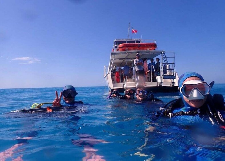 A group of scuba divers in the ocean with a boat in the background. 2