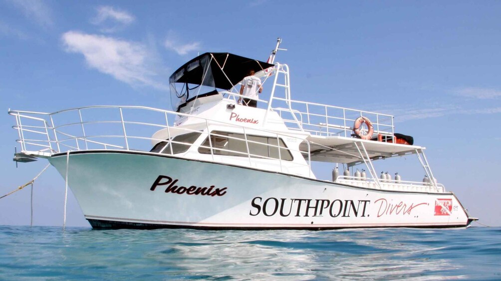 A white boat named 'Phoenix' with 'SOUTHPOINT Divers' written on the side, floating on calm blue water. 4
