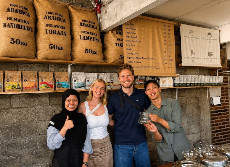 Four people standing in front of sacks labeled with coffee types and weights, with a menu listing coffee options and temperatures. 1