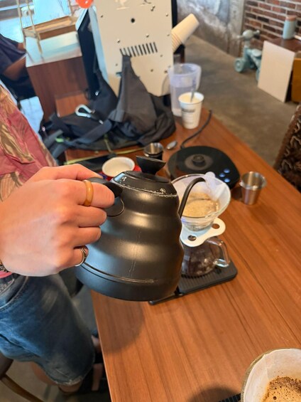 A person holding a black coffee pot. 2