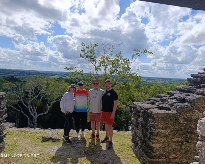 A group of people standing on a rocky outcrop with a view of a landscape and a clear sky. 2