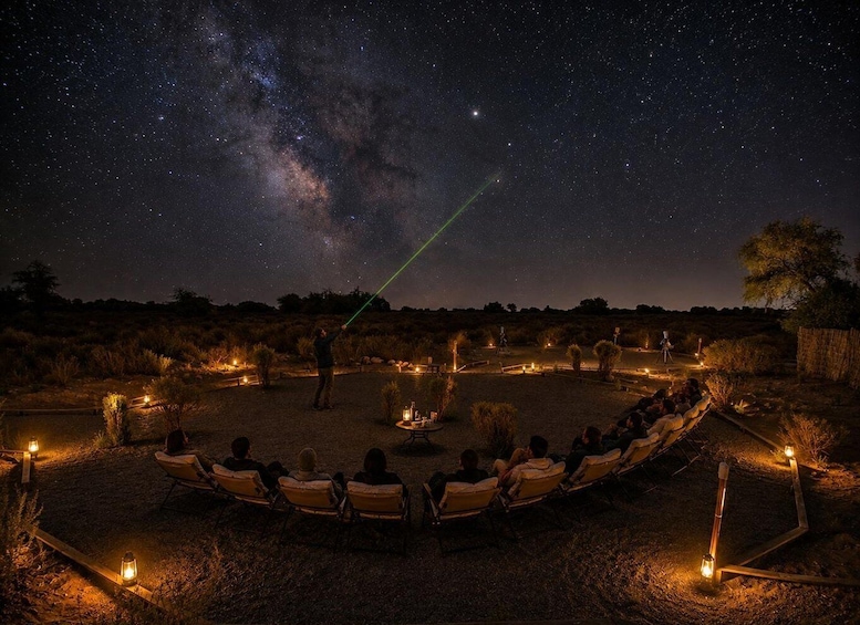 A group of people sitting in a circle under a starry sky, with a telescope pointed at the Milky Way. 1