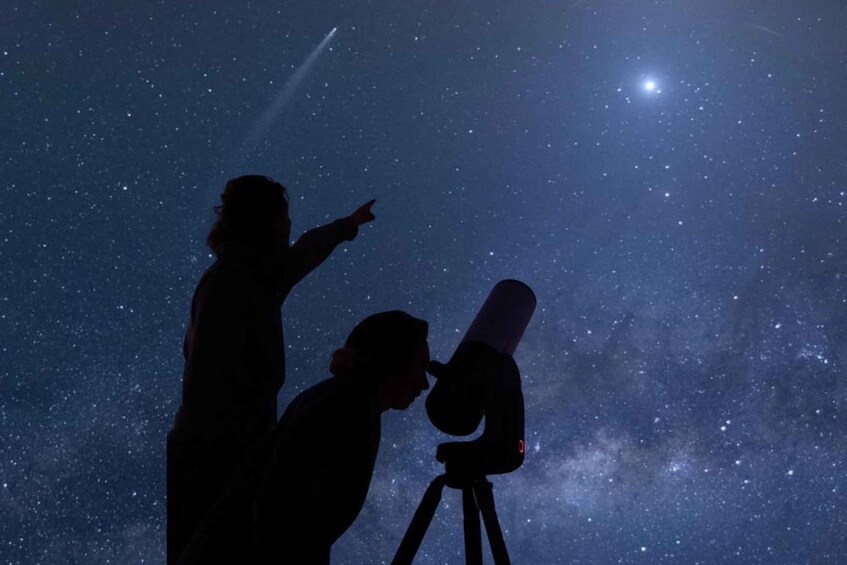 Two people observing the night sky with a telescope. 1