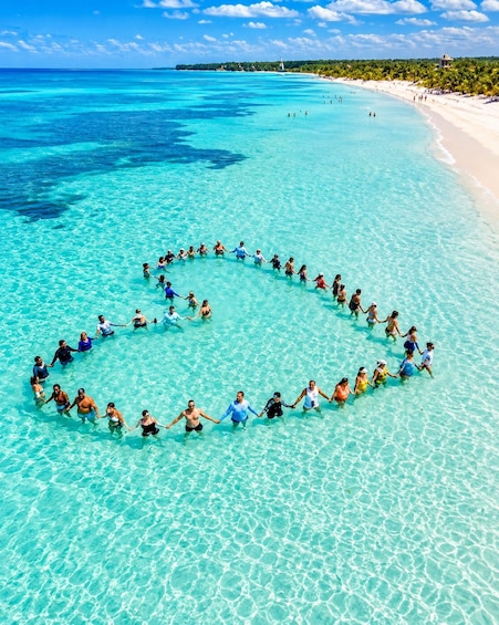 A group of people forming a heart shape in the shallow waters of a beach. 1