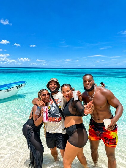 A group of people on a beach with clear turquoise water and a boat in the background. 5