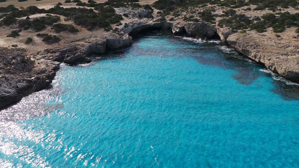 A turquoise coastal area with rocky terrain and a natural arch formation. 2