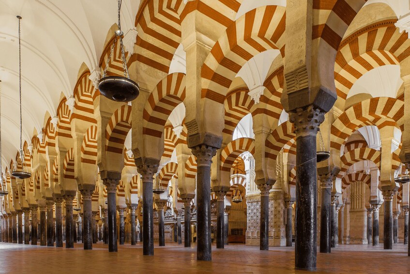 A mosque interior with arches and columns. 4