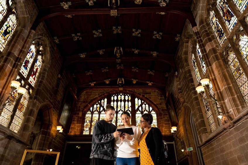 A group of people inside a cathedral with stained glass windows and a high arched ceiling. 1