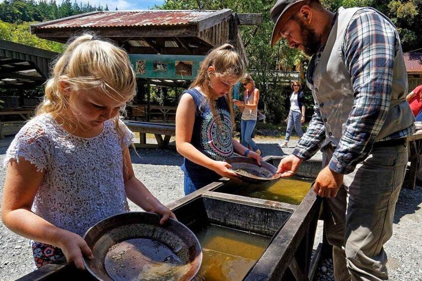 Des personnes assistent à une démonstration de travail du métal selon des méthodes traditionnelles, avec une structure en bois en arrière-plan. 3