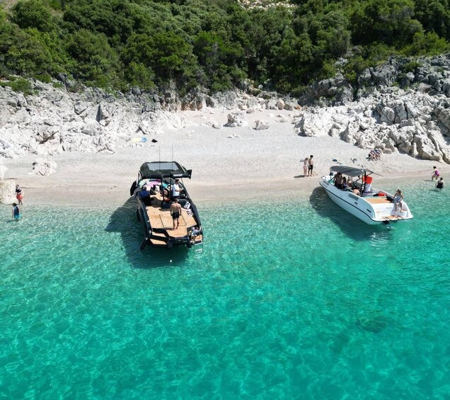 A boat docked on a beach with clear turquoise water and rocky terrain in the background. 2