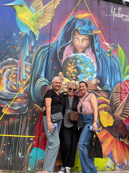 A mural with a woman holding a globe, surrounded by colorful birds and flowers. 2