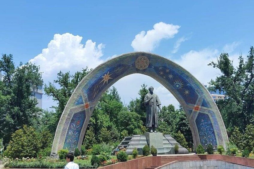 A statue under a colorful archway with a starry design, surrounded by greenery. 2