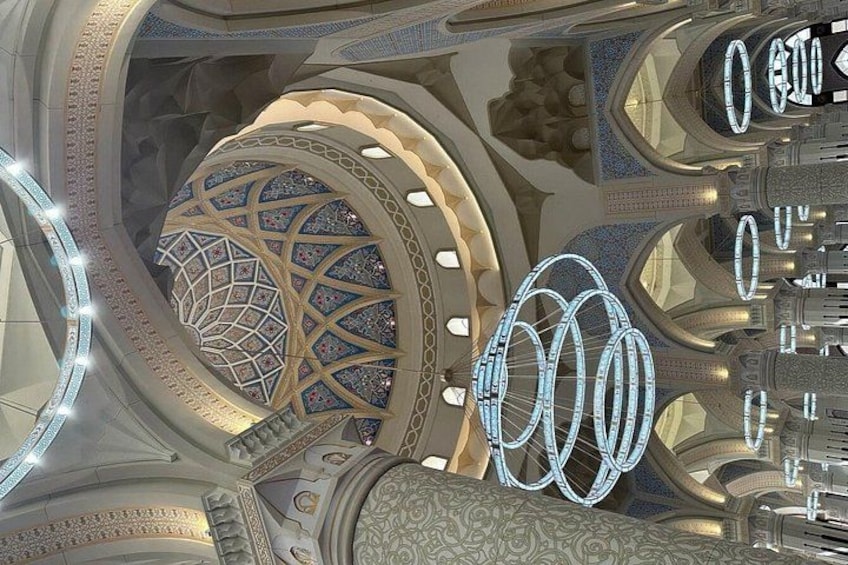 A grand architectural interior with ornate designs, a large dome, and circular light fixtures. 4