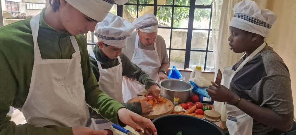 A group of people wearing chef hats and aprons, preparing food in a kitchen. 2