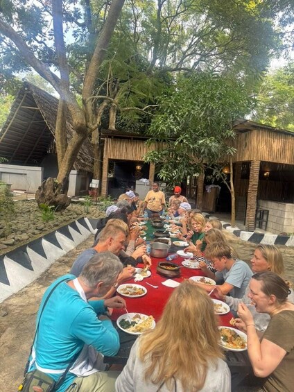 A group of people dining outdoors around a large table. 4
