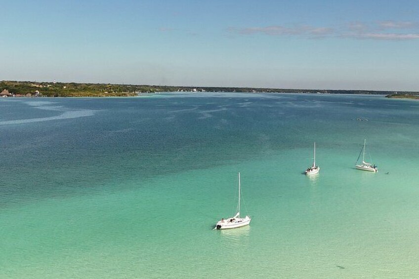 A turquoise sea with three sailboats anchored. 1